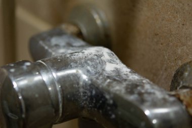 Duş karıştırıcı musluğu, kireç pulu, beyaz tebeşir yatağı, lekeler ve pas ile yakın plan. Bakım ve temizlik kireçtaşı tesisat konsepti.