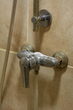 Duş karıştırıcı musluğu, kireç pulu, beyaz tebeşir yatağı, lekeler ve pas ile yakın plan. Bakım ve temizlik kireçtaşı tesisat konsepti.