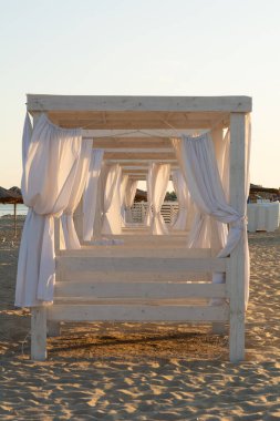 Batan güneş ışınlarında sahil çadırları, sahil manzarası.