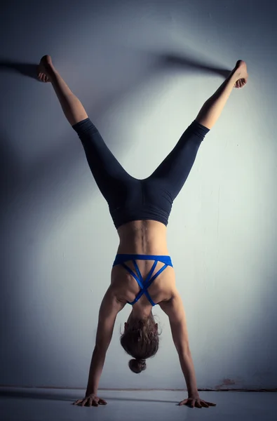 Kvinnan gör hand stand mot en vägg — Stockfoto