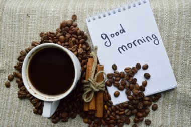 Bir fincan sıcak kahve, kahve fasulye, not defteri, cinna mon, baharatlar