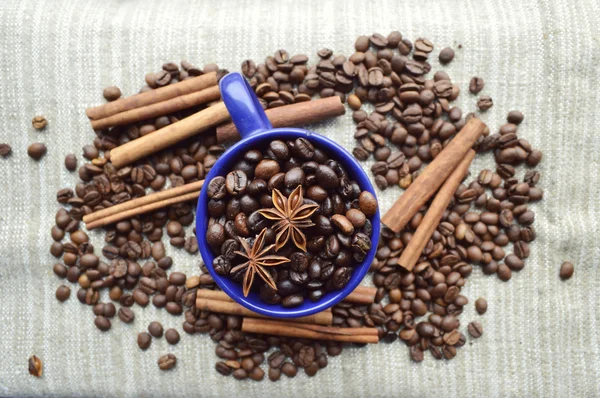 Tasse pleine de grains de café, bâtonnets de cannelle, anis étoilé, gros plan — Photo