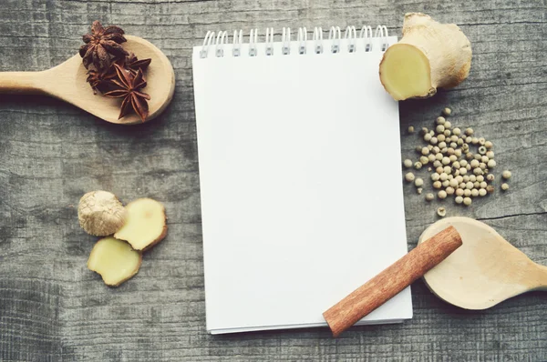 Condimentos, especias, libro de recetas, Bloc de notas, escribir, pimienta, guisantes, pimiento rojo, pimienta negra, cardamomo, anís estrellado, canela, cilantro, palitos de canela, clavo de olor, estrella — Foto de Stock