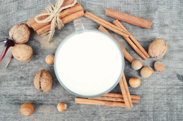 Tazza di latte caldo con cannella, spezie e nocciole, noci, primo piano su fondo di legno — Foto Stock