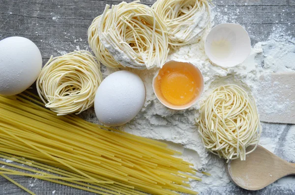 Stilleven met ruwe huisgemaakte pasta en ingrediënten voor pasta... proces van koken pasta — Stockfoto