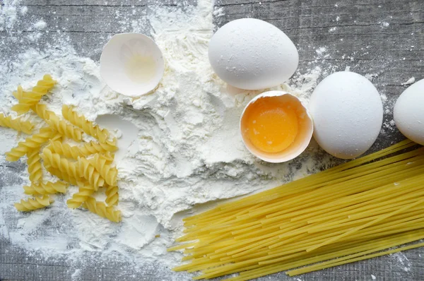 Stilleven met ruwe huisgemaakte pasta en ingrediënten voor pasta... proces van koken pasta — Stockfoto
