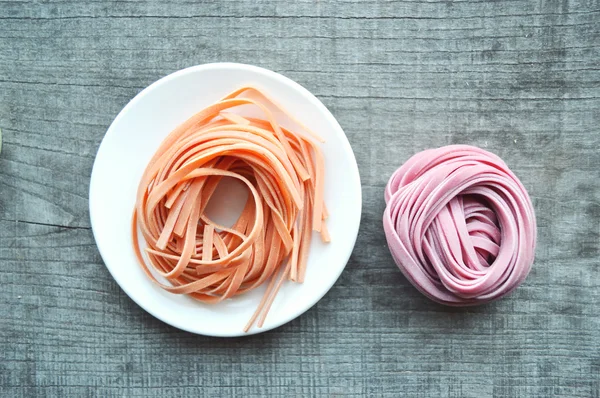 Pâtes italiennes crues colorées sur fond en bois — Photo