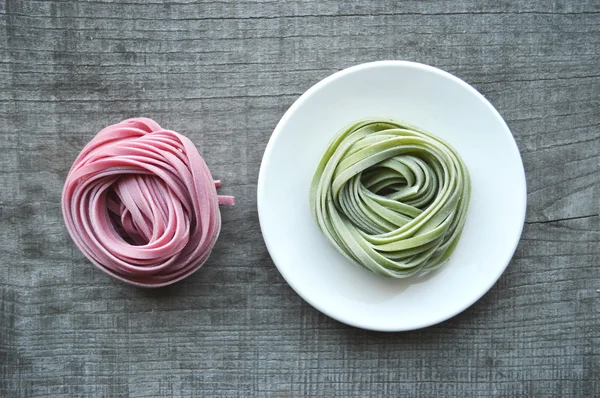 Färgglada raw italiensk pasta på trä bakgrund — Stockfoto