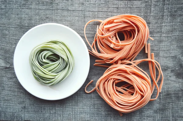 Bunte rohe italienische Pasta auf hölzernem Hintergrund — Stockfoto