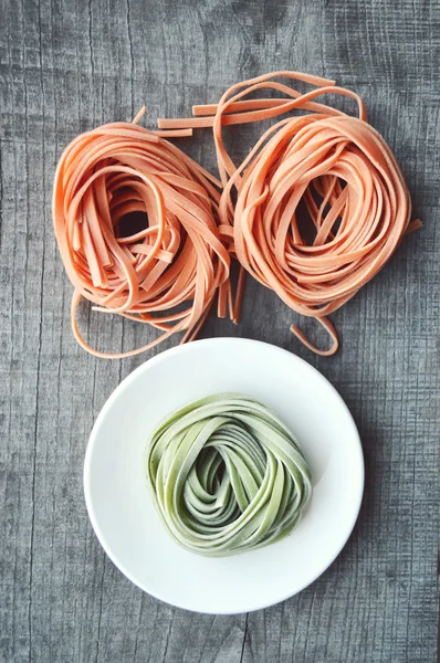 Bunte rohe italienische Pasta auf hölzernem Hintergrund — Stockfoto