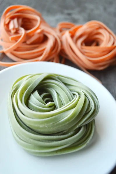 Bunte rohe italienische Pasta auf hölzernem Hintergrund — Stockfoto