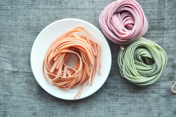 Colorful raw italian pasta on wooden background — Stock Photo, Image