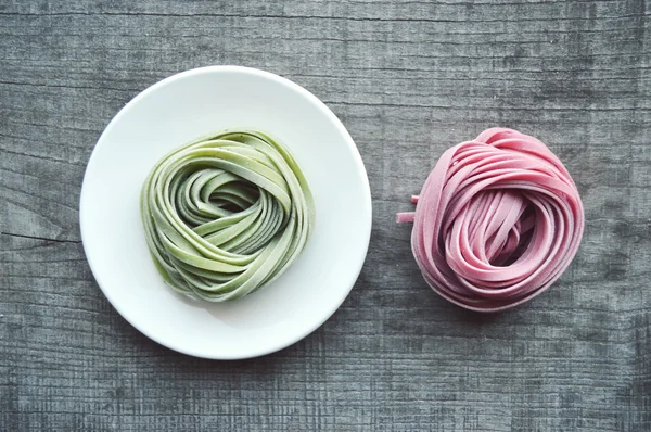 Colorful raw italian pasta on wooden background — Stock Photo, Image