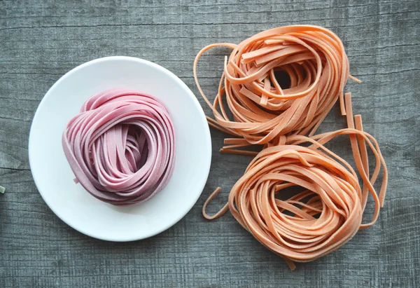 Pâtes italiennes crues colorées sur fond en bois — Photo