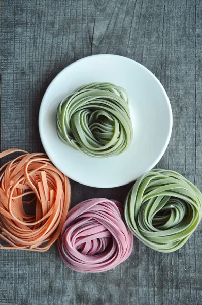 Ahşap arka plan üzerinde renkli ham İtalyan makarna