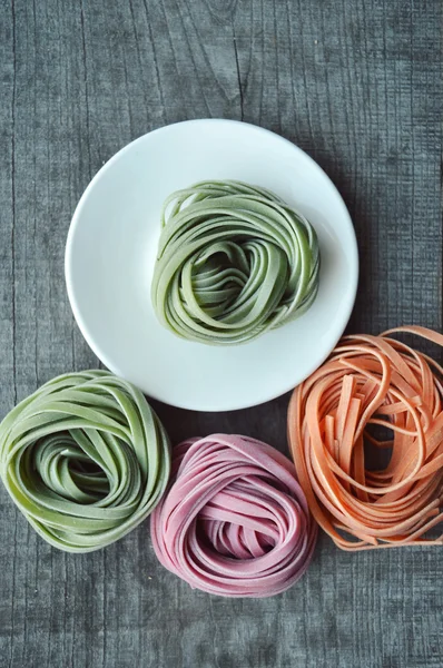 Bunte rohe italienische Pasta auf hölzernem Hintergrund — Stockfoto