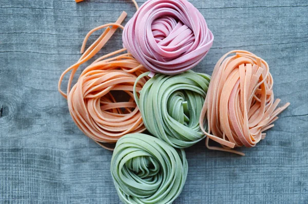 Colorful raw italian pasta on wooden background — Stock Photo, Image