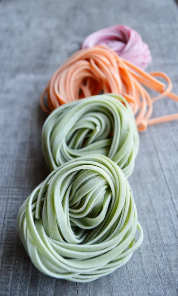 Colorful raw italian pasta on wooden background — Stock Photo, Image