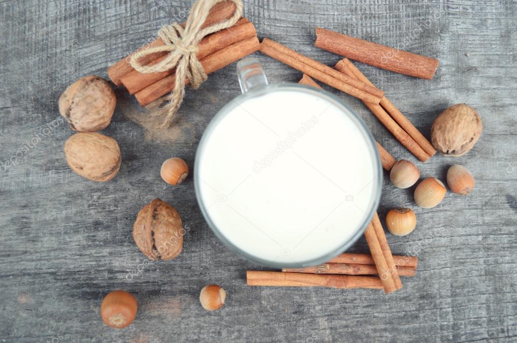 Cup of hot milk with cinnamon , Spices and hazelnuts, walnuts, closeup on wooden background