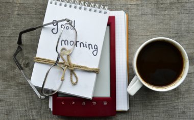 Kırmızı e-gözlük, kitap okuma, not defteri, sıcak kahve ahşap arka plan üzerinde