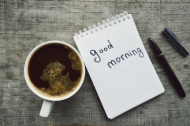 Bir fincan sıcak kahve, kahve fasulye, not defteri, tarçın, baharatlar