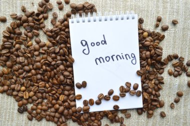 Bir fincan sıcak kahve, kahve fasulye, not defteri, tarçın, baharatlar