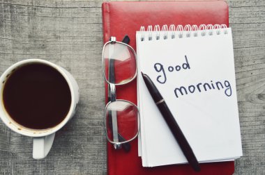 Kırmızı e-gözlük, kitap okuma, not defteri, sıcak kahve ahşap arka plan üzerinde