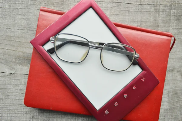 E-book on wooden background.Notepad, diary, record, reading glasses — стоковое фото