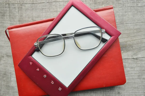 E-book sur fond en bois.Bloc-notes, journal, disque, lunettes de lecture — Photo