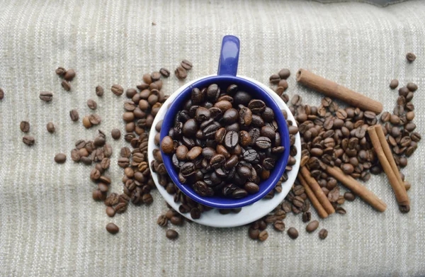 Tasse pleine de grains de café, bâtonnets de cannelle, anis étoilé, gros plan — Photo