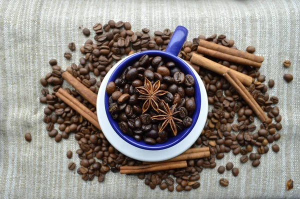 Tasse pleine de grains de café, bâtonnets de cannelle, anis étoilé, gros plan — Photo