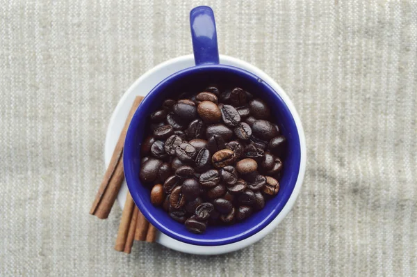 Tasse pleine de grains de café, bâtonnets de cannelle, anis étoilé, gros plan — Photo