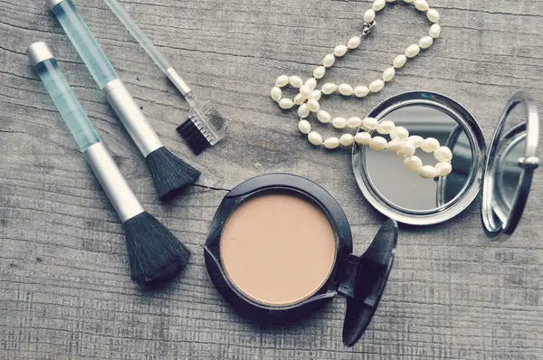 Maquillaje Cepillo de delineador de ojos con botella, conjunto de cosméticos, maquillaje y cepillos, polvo, hojaldre, rímel, delineador de ojos en la mesa de madera — Foto de Stock