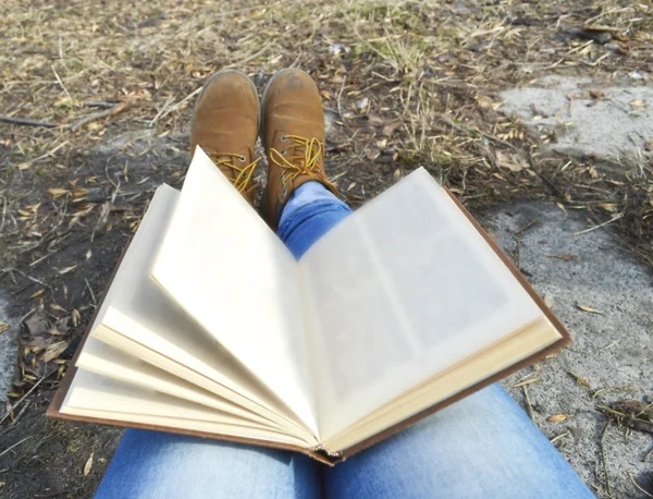 Gadis dalam sepatu bot coklat membaca buku yang menarik di taman — Stok Foto