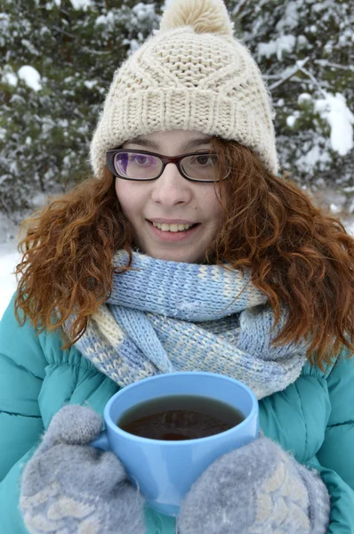 黒髪の少女は、公園で本を読んで、紅茶、コーヒー、ココアを飲むターコイズ ブルー ジャケット、身体毛糸の帽子、光の青いスカーフに身を包んだ — ストック写真