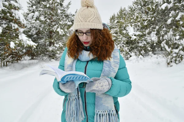 Ciemnowłosa dziewczyna ubrana w turkus kurtkę, ciała wełnisty kapelusz i szalik niebieskie światło, czytanie książki w parku, picie herbaty, kawy, kakao — Zdjęcie stockowe