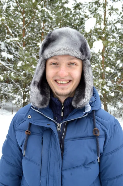 Młody, ciemnowłosą człowieka, ciepło ubrany, stojący w lesie śnieżny — Zdjęcie stockowe