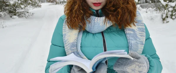 Chica de cabello oscuro vestida con una chaqueta turquesa, sombrero de lana corporal, y una bufanda azul claro, leyendo un libro en el Parque, bebiendo té, café, cacao —  Fotos de Stock