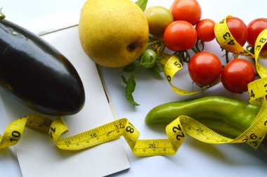 Sebze ve meyve kilo kaybı, bir ölçüm bandı, diyet, kilo kaybı, ölçüm bandı, sağlıklı beslenme, sağlıklı yaşam konsepti. Not Defteri, günlük, patlıcan, elma, armut