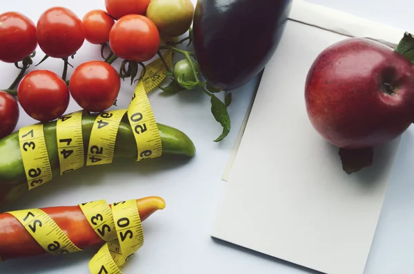 Verduras y frutas para bajar de peso, una cinta métrica, dieta, pérdida de peso, cinta métrica, alimentación saludable, concepto de estilo de vida saludable.Bloc de notas, diario, berenjena, manzana, pera — Foto de Stock