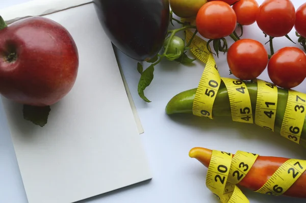 Verduras y frutas para bajar de peso, una cinta métrica, dieta, pérdida de peso, cinta métrica, alimentación saludable, concepto de estilo de vida saludable.Bloc de notas, diario, berenjena, manzana, pera — Foto de Stock