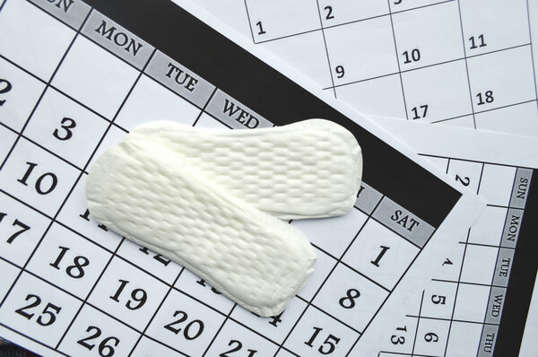 Woman hygiene protection, close-up.menstruation calendar with cotton tampons,orange Gerber,Sanitary pads on a red background