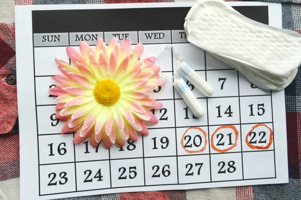 Protección de la higiene de la mujer, close-up.menstruation calendario con tampones de algodón, naranja Gerber, almohadillas sanitarias sobre un fondo rojo — Foto de Stock