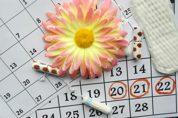 Calendario de menstruación con tampones de algodón, gerberas naranjas y toallas sanitarias — Foto de Stock