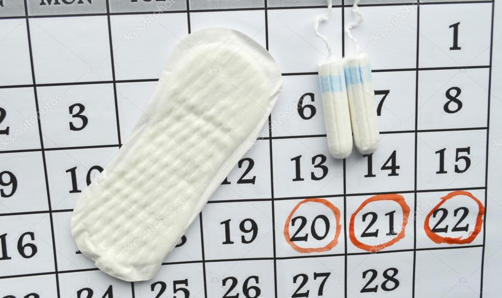 Woman hygiene protection, close-up.menstruation calendar with cotton tampons,orange Gerber,Sanitary pads on a red background