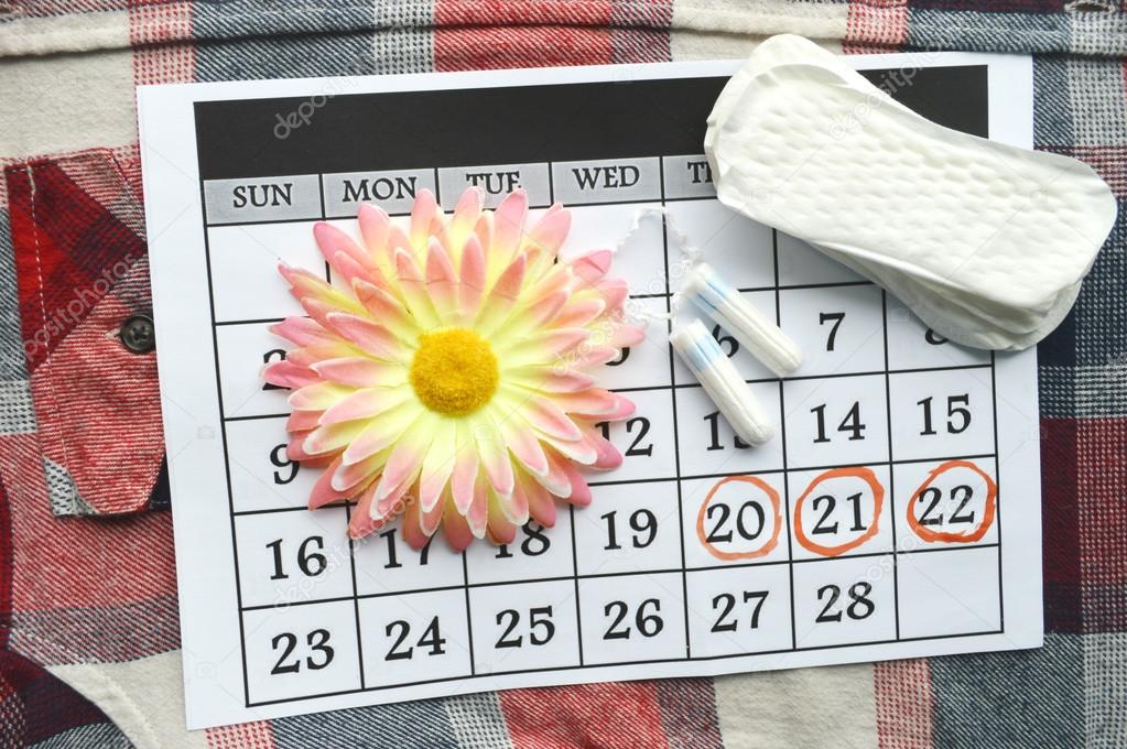 Woman hygiene protection, close-up.menstruation calendar with cotton tampons,orange Gerber,Sanitary pads on a red background