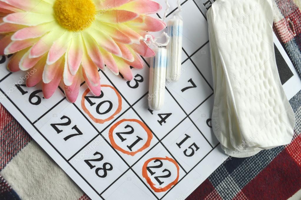 Woman hygiene protection, close-up.menstruation calendar with cotton tampons,orange Gerber,Sanitary pads on a red background