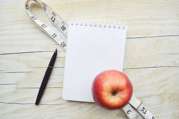 Bloco de notas com fita métrica e maçã — Fotografia de Stock