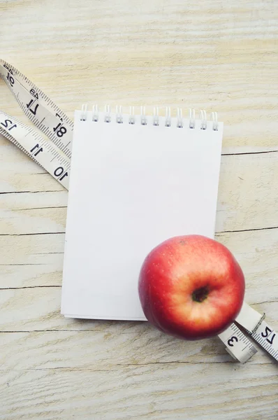 Bloc de notas con cinta métrica y manzana — Foto de Stock