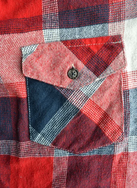 Detail of a red plaid button up style shirt.